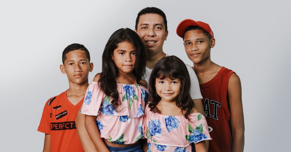 A joyful family portrait featuring a father and four children against a white background.